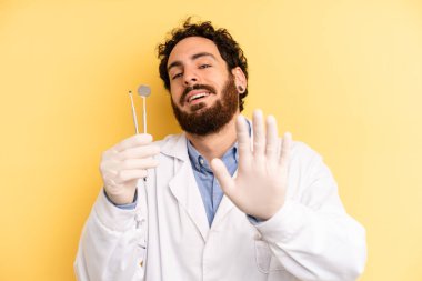 Genç adam mutlu bir şekilde gülümsüyor, el sallıyor, sizi selamlıyor ve selamlıyor. dişçi kavramı