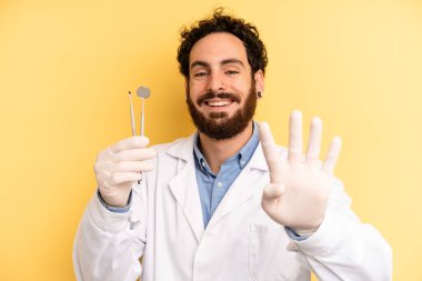 Genç adam gülümsüyor ve arkadaş canlısı görünüyor, dört numarayı gösteriyor. dişçi kavramı