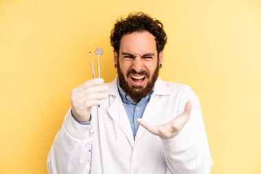 Genç adam sinirli, sinirli ve sinirli görünüyor. dişçi kavramı