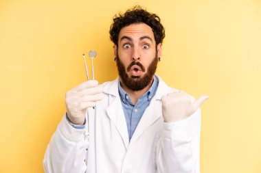 Genç adam inançsızlıktan şaşkın şaşkın bakıyor. dişçi kavramı