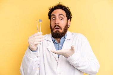 Genç adam şaşırmış ve şok olmuş görünüyor. Çenesi düşmüş ve elinde bir nesne tutuyor. dişçi kavramı