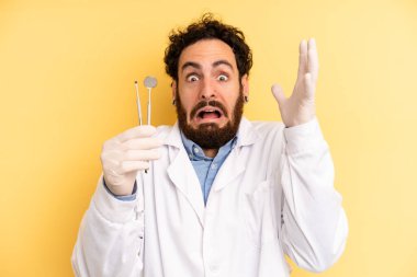 Genç adam ellerini havaya kaldırarak çığlık atıyor. dişçi kavramı