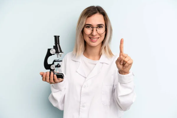 Blonde Woman Smiling Looking Friendly Showing Number One Scientist Student — Stockfoto