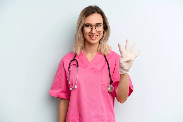 Blonde Woman Smiling Looking Friendly Showing Number Four Nurse Concept — Zdjęcie stockowe