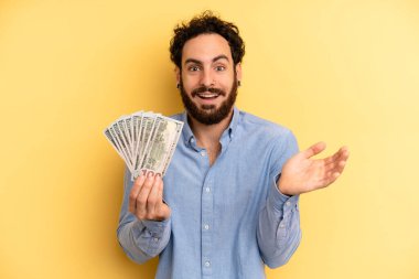 Genç adam kendini mutlu hissediyor ve inanılmaz bir şeye hayret ediyor. Dolar banknotları konsepti