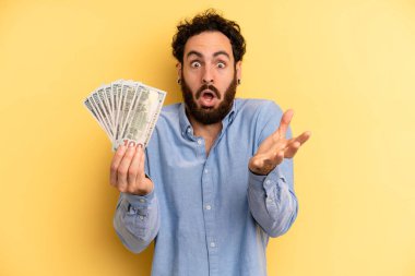 Genç adam inanılmaz bir sürprizle şaşırdı, şok oldu ve hayrete düştü. Dolar banknotları konsepti