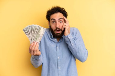 Genç adam şaşırmış görünüyor, yeni bir düşünce, fikir ya da konseptin farkına varıyor. Dolar banknotları konsepti