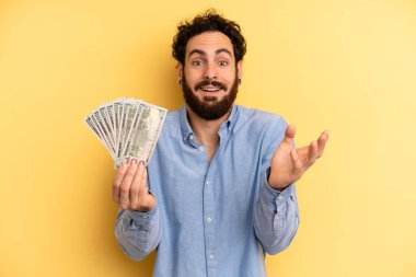 Genç adam kendini mutlu hissediyor, bir çözüm ya da fikir bulduğuna şaşırıyor. Dolar banknotları konsepti