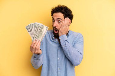 Genç adam mutlu, heyecanlı ve şaşırmış hissediyor. Dolar banknotları konsepti
