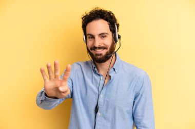 Genç adam gülümsüyor ve arkadaş canlısı görünüyor, dört numarayı gösteriyor. tele pazarlamacı kavramı