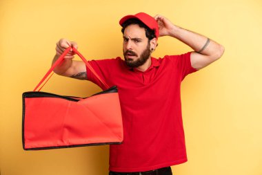Genç adam şaşkın ve kafası karışmış hissediyor, başını kaşıyor. Pizza teslimatı kavramı