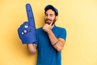 Genç adam mutlu, kendinden emin ve elleri çenesinde gülümsüyor. Bir el fan konsepti