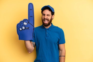 Neşeli ve asi tavırlı genç bir adam, şaka yapıyor ve dilini dışarı çıkarıyor. Bir el fan konsepti