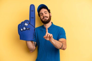 Genç adam gülümsüyor ve arkadaş canlısı görünüyor, bir numarayı gösteriyor. Bir el fan konsepti