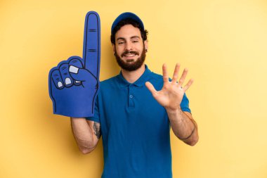 Genç adam gülümsüyor ve arkadaş canlısı görünüyor, beş numarayı gösteriyor. Bir el fan konsepti