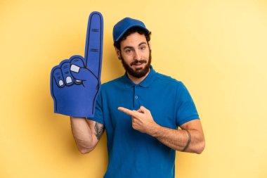 Genç adam neşeyle gülümsüyor, mutlu hissediyor ve bir tarafı işaret ediyor. Bir el fan konsepti