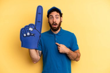 Şok olmuş ve ağzı açık, kendini işaret eden genç bir adam. Bir el fan konsepti
