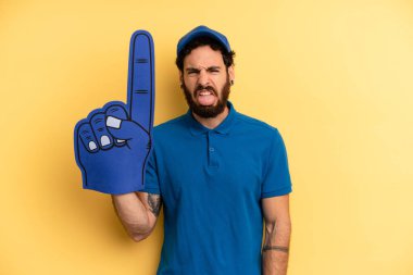 Genç adam iğreniyor, sinirleniyor ve dilini çıkarıyor. Bir el fan konsepti