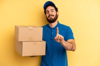 Genç adam gülümsüyor ve arkadaş canlısı görünüyor, bir numarayı gösteriyor. Şirket çalışanı konsepti