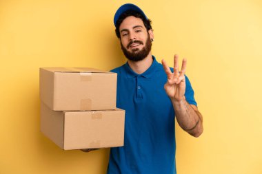 Genç adam gülümsüyor ve arkadaş canlısı görünüyor, üç numarayı gösteriyor. Şirket çalışanı konsepti