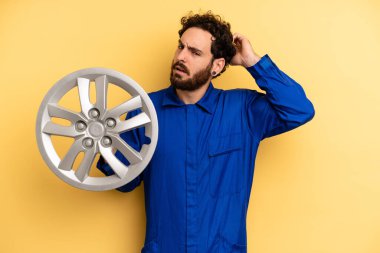 Genç adam mutlu bir şekilde gülümsüyor ve hayal kuruyor ya da şüphe ediyor. araba mekaniği kavramı