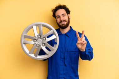 Genç adam gülümsüyor ve iki numarayı gösteriyor. araba mekaniği kavramı