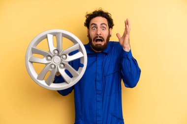 Genç adam ellerini havaya kaldırarak çığlık atıyor. araba mekaniği kavramı