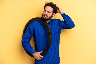 Genç adam şaşkın ve kafası karışmış hissediyor, başını kaşıyor. motor mekaniği kavramı