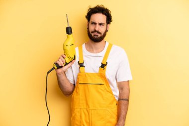 Genç adam üzgün, üzgün ya da kızgın hissediyor ve yana bakıyor. Matkap ustası.