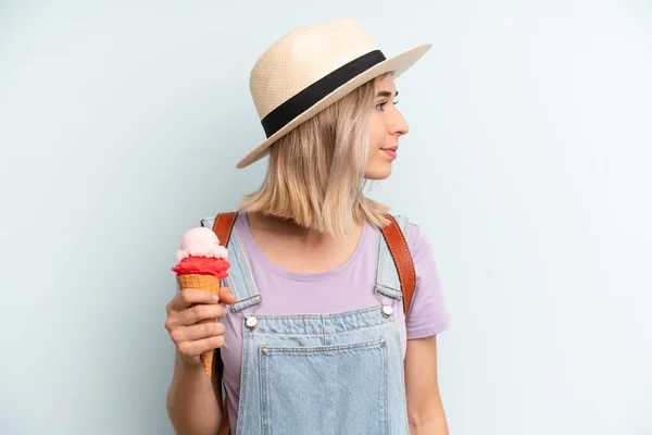 blonde woman on profile view thinking, imagining or daydreaming. ice cream and summer concept