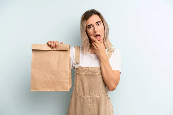 blonde woman with mouth and eyes wide open and hand on chin. take away delivery concept