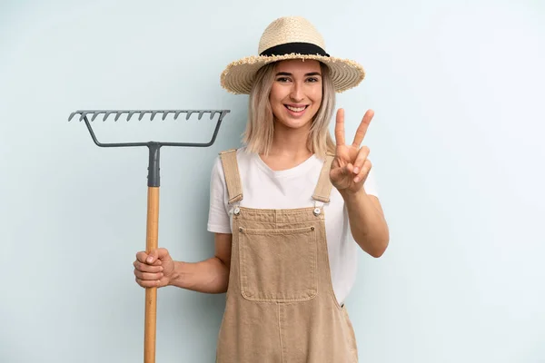 Blonde Woman Smiling Looking Happy Gesturing Victory Peace Farmer Rake — Stockfoto