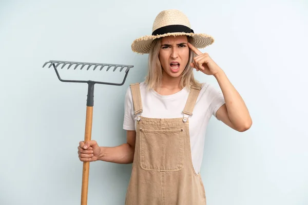 Blonde Woman Feeling Confused Puzzled Showing You Insane Farmer Rake — Stockfoto