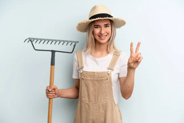 Blonde Vrouw Lacht Ziet Vriendelijk Uit Toont Nummer Twee Landbouwer — Stockfoto