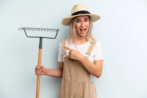 Blonde Woman Looking Excited Surprised Pointing Side Farmer Rake Cocnept — Fotografia de Stock
