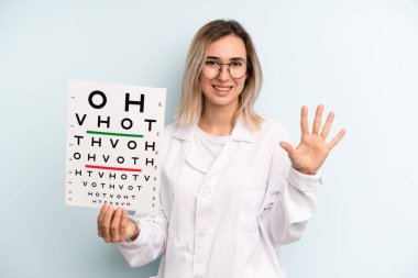 Sarışın kadın gülümsüyor ve arkadaş canlısı görünüyor, beş numarayı gösteriyor. optik görüş testi konsepti