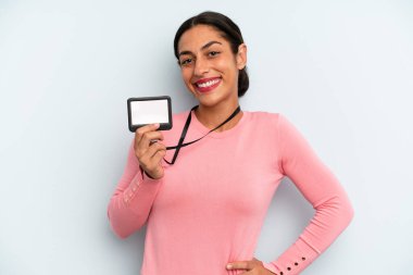 hispanic woman smiling happily with a hand on hip and confident. vip pass card