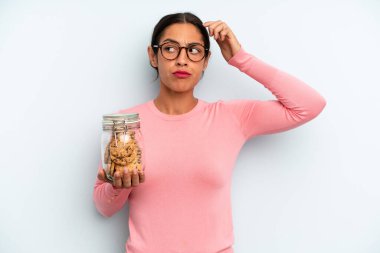 İspanyol kadın şaşkın ve kafası karışık, kaşınıyor. Ev yapımı kurabiye konsepti