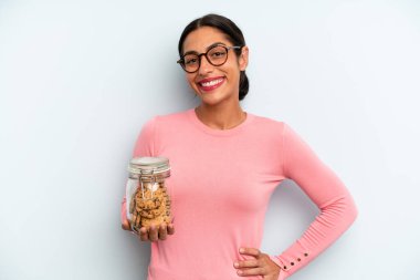 İspanyol kadın mutlu bir şekilde gülümsüyor, eli kalçasında ve kendinden emin. Ev yapımı kurabiye konsepti