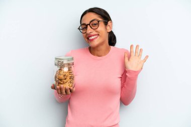 İspanyol kadın mutlu bir şekilde gülümsüyor, el sallıyor, sizi selamlıyor ve selamlıyor. Ev yapımı kurabiye konsepti