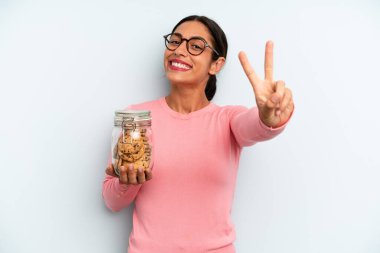İspanyol kadın gülümsüyor ve arkadaş canlısı görünüyor, iki numarayı gösteriyor. Ev yapımı kurabiye konsepti