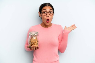 İspanyol kadın şaşırmış ve şok olmuş görünüyor. Çenesi düşmüş ve elinde bir nesne tutuyor. Ev yapımı kurabiye konsepti