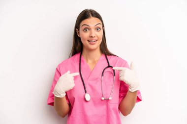 Güzel bir kadın mutlu hissediyor ve heyecanla kendini işaret ediyor. hemşire konsepti