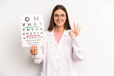 Güzel bir kadın kendini mutlu hissediyor, iyi bir jestle onaylıyor. optik görüş testi konsepti