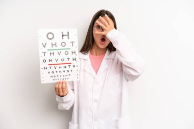 Güzel bir kadın şok olmuş, korkmuş ya da korkmuş görünüyor. Yüzü elle kapatılmış. optik görüş testi konsepti