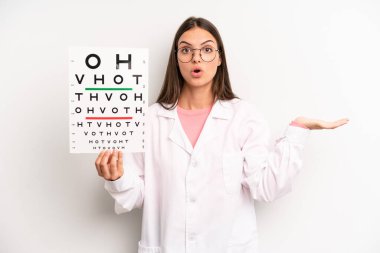 Güzel kadın şaşırmış ve şok olmuş görünüyor. Çenesi düşmüş ve elinde bir nesne tutuyor. optik görüş testi konsepti