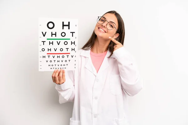 pretty woman smiling confidently pointing to own broad smile. optical vision test concept