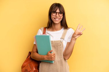 Güzel bayan gülümsüyor ve arkadaş canlısı görünüyor, üç numarayı gösteriyor. Üniversite öğrencisi konsepti