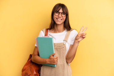 Güzel bayan gülümsüyor ve arkadaş canlısı görünüyor, ikinciyi gösteriyor. Üniversite öğrencisi konsepti