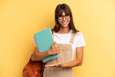 Güzel bir kadın neşeyle gülümser, mutlu hisseder ve bir konsept gösterir. Üniversite öğrencisi konsepti